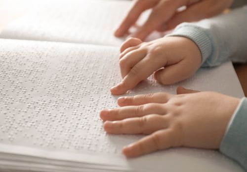 A child reading braille with an adult